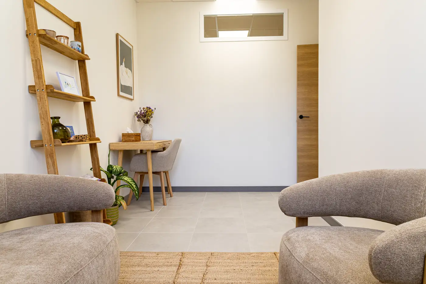 Consulta de psicología en Málaga con sillones tapizados, escritorio de madera y estantería decorativa