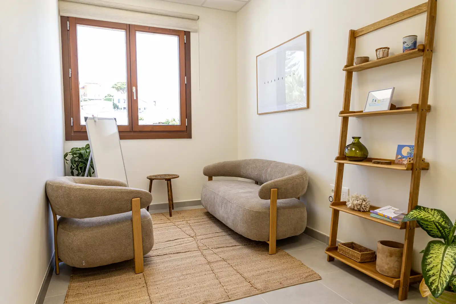 Sala de psicología en Málaga con sofá tapizado, estantería de madera y luz natural de ventana